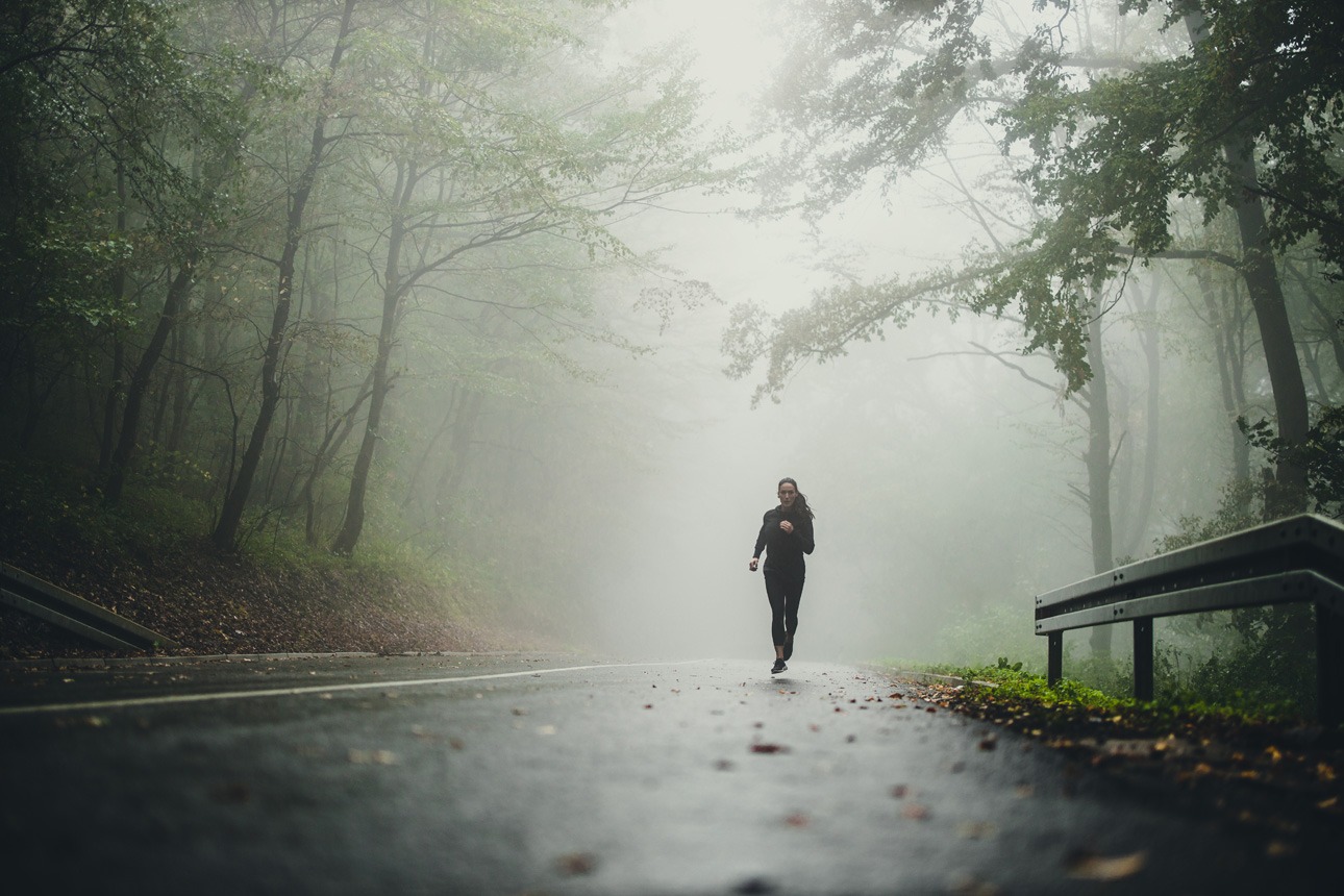 Femme courant dans la brume d'un sous-bois