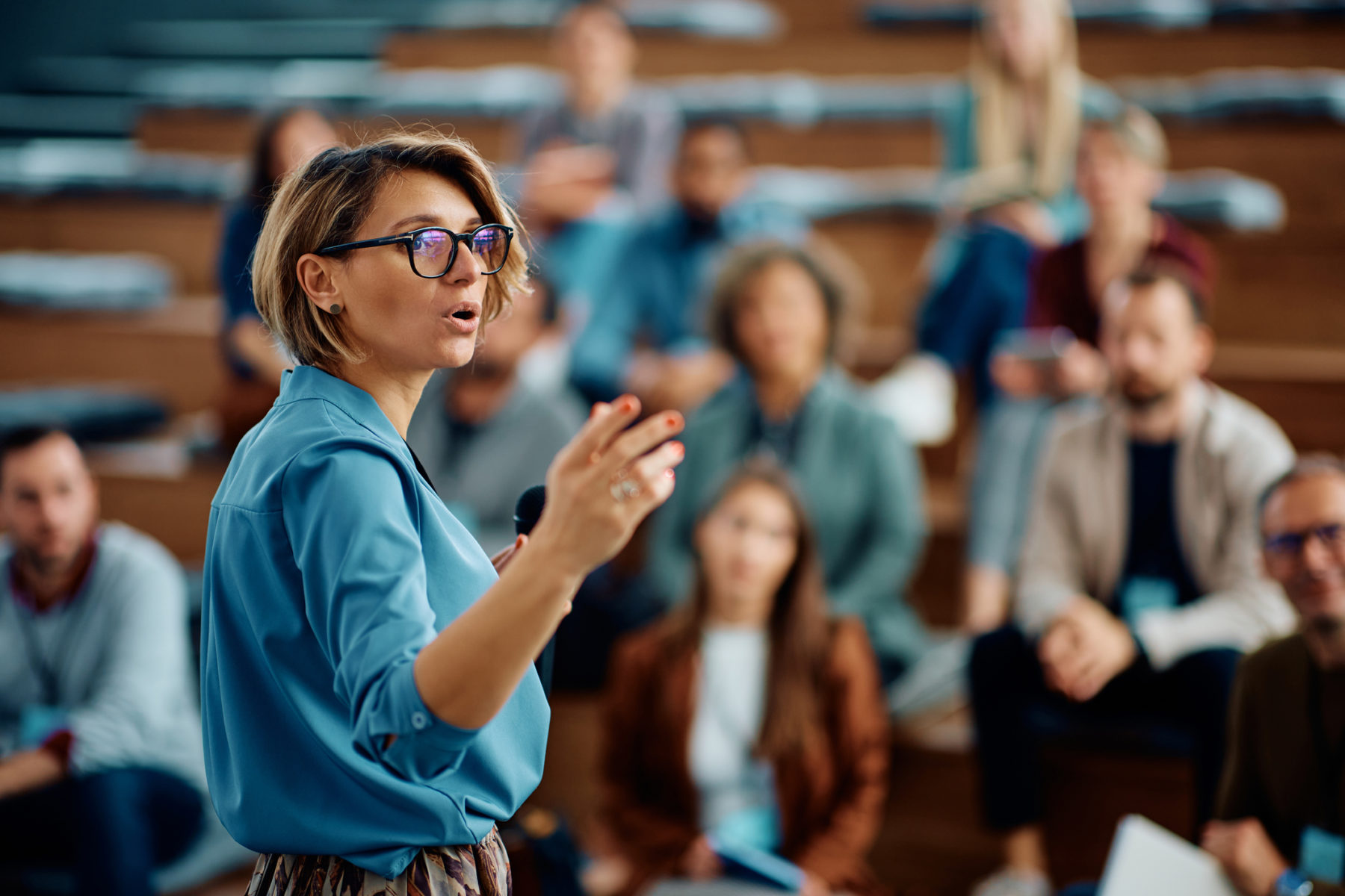 Une femme parle à un auditoire. Elle semble avoir confiance en elle et être très professionnelle