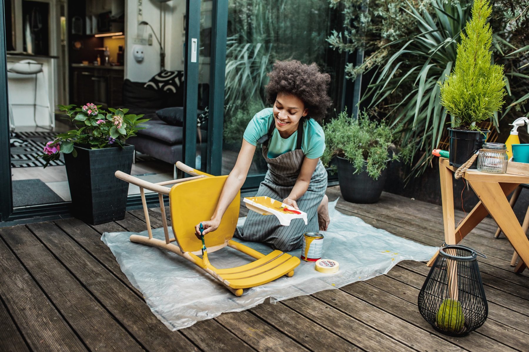 Une femme est en train de repeindre une chaise sur sa terrasse